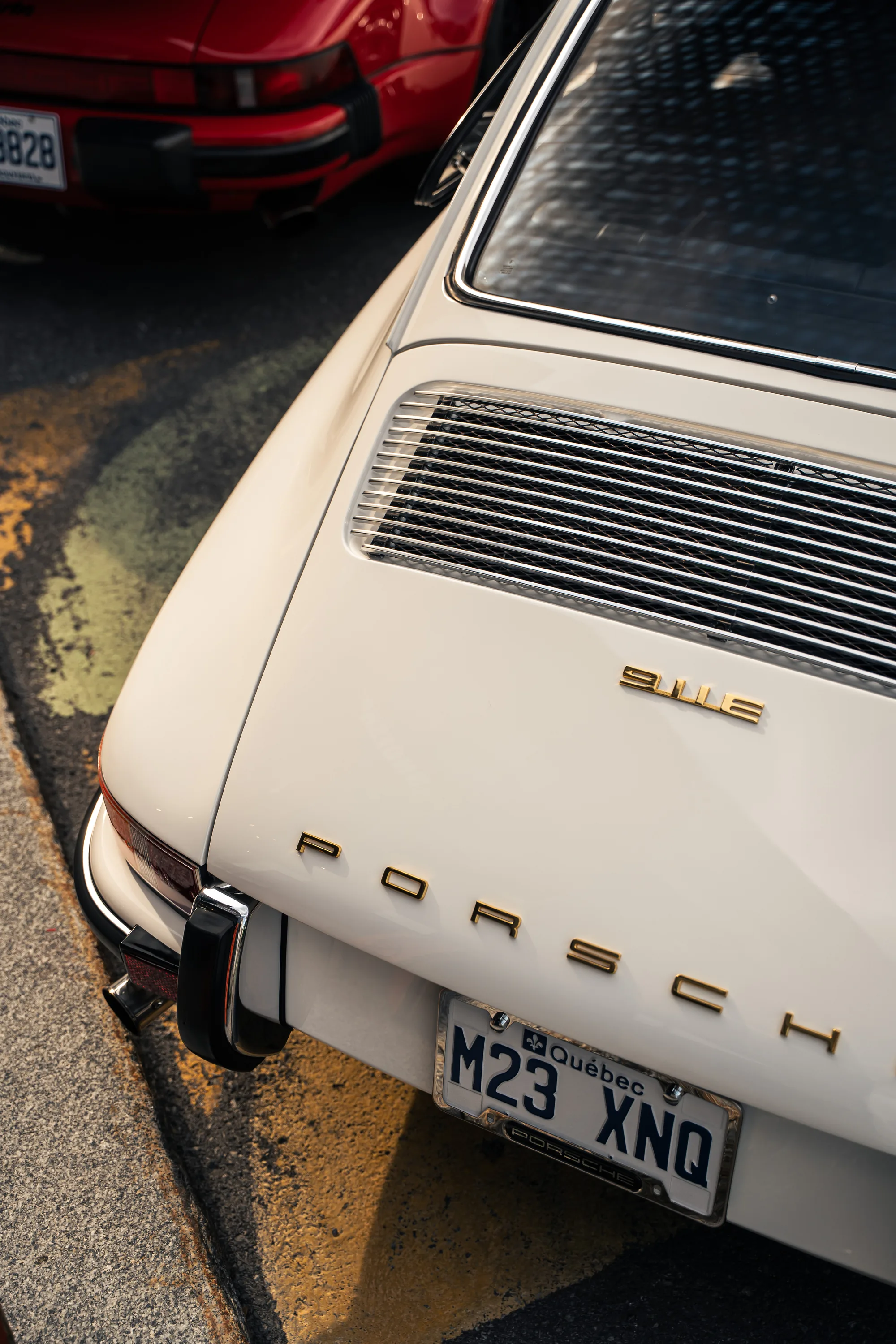 The tail of a white air-cooled Porsche 911 S, its Québec plate in the morning sun.